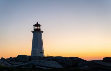 Phare sur un terrain rocheux au coucher du soleil.