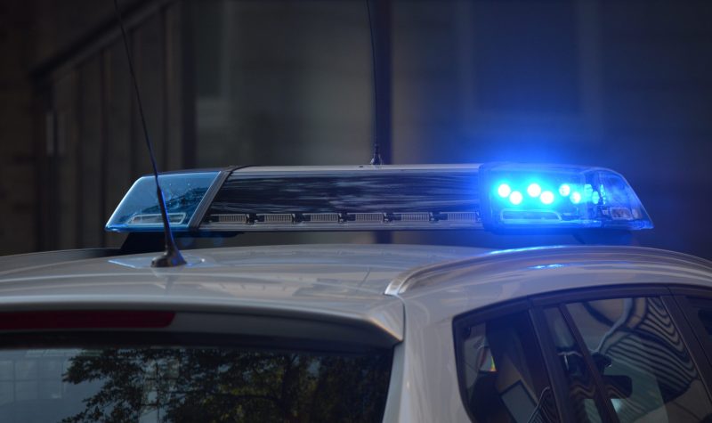 A stock photo of blue police sirens on top of a car against a gray background