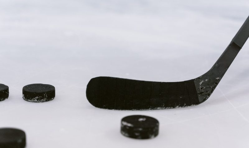 a close up photo of a hockey stick and a puck on ice