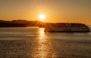 A BC Ferries vessel sails against a sunlit background.