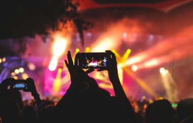 Une personne tenant son téléphone pour prendre une vidéo d'un concert