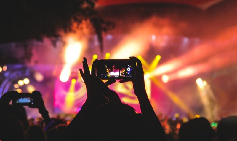 Une personne tenant son téléphone pour prendre une vidéo d'un concert