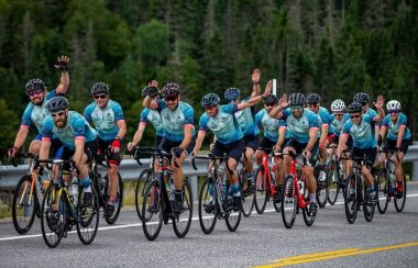 Un groupe de cyclistes sur la route en uniforme bleu faisant des salutations de la main