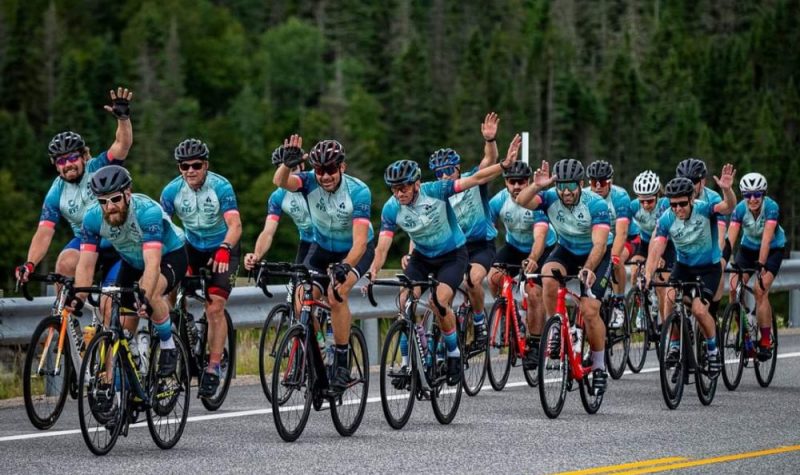 Un groupe de cyclistes sur la route en uniforme bleu faisant des salutations de la main