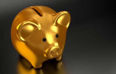 Gold piggy bank sitting on a black surface.