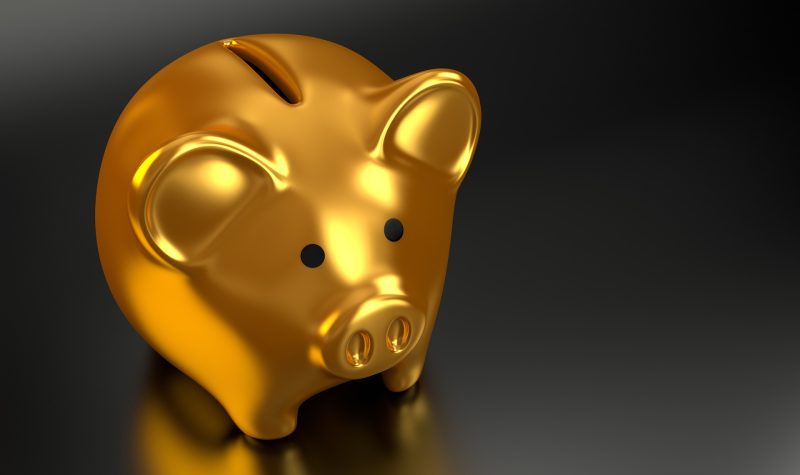 Gold piggy bank sitting on a black surface.