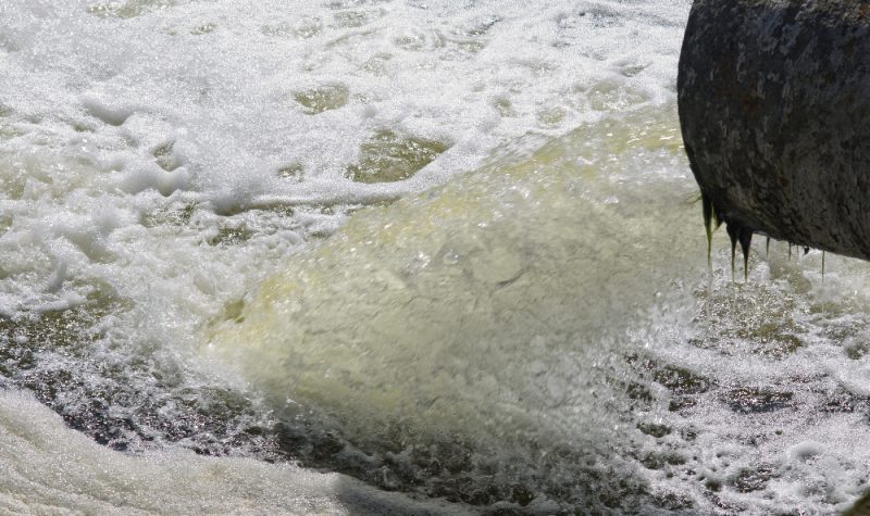 Un tuyaux laisse déverser de l'eau à fort débit dans un cours d'eau
