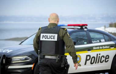 Un policier de la Sûreté du Québec marche de dos en direction de son véhicule de police