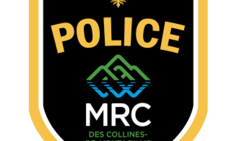 The logo of the MRC des Collines Police, with gold letters on a black background above a logo of green and blue mountains.