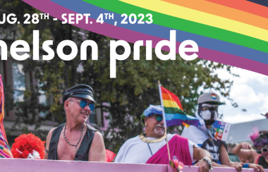 People smiling on a parade float with pride flags.