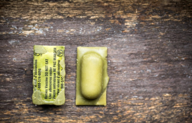 A rabies vaccine bait: Yellow capsule with black lettering on it. Placed on a wooden surface.