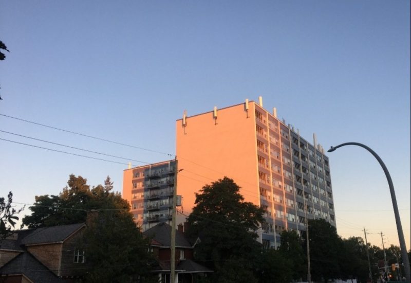 An Ottawa apartment building is seen at sunset in front of a road