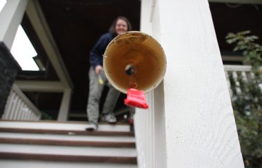 Candy comes out of the end of a homemade pipe. A woman stands up a staircase in the background.