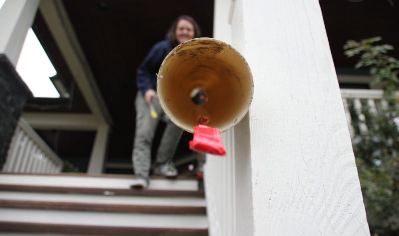 Candy comes out of the end of a homemade pipe. A woman stands up a staircase in the background.