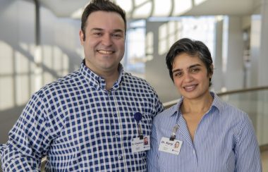 A man and woman smile at the camera.