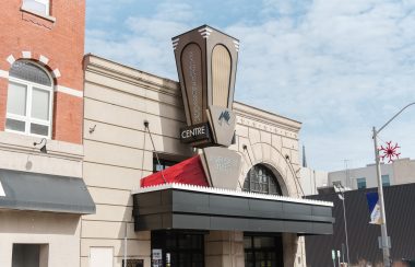 Front entrance of The Sanderson Centre. The sign displaying the name sits over top of the front entrance doors and a black awning.