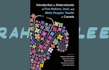 a textbook with a quilted fabric around a stethoscope is the cover of a textbook about Indigenous health