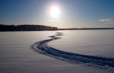 Un tracé de motoneige est visible sur une surface plane recouverte de neige.