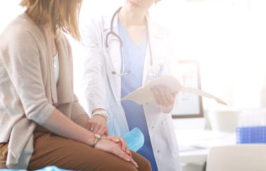 Médecin et patient discutant de quelque chose assis à la table. La dame médecin tient le bras de la patiente. Concept de médecine et de soins de santé.