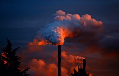 Cheminées d'usine qui libère beaucoup de fumé dans un ciel bleu et rouge