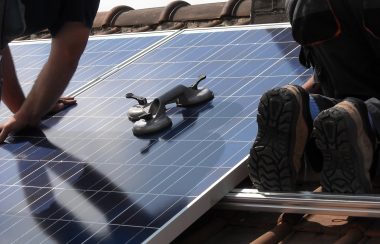 des travailleurs installent des panneaux solaires sur un toit de maison