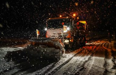 A snow plow is seen during a stowstorm at night in a stock image