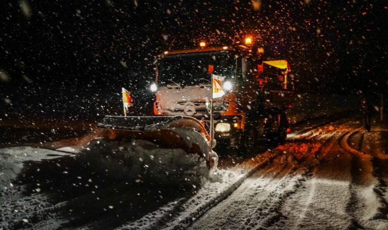 A snow plow is seen during a stowstorm at night in a stock image