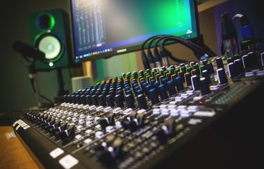 Console de radio avec des micros, un ordinateur et un haut-parleurs qui se retrouvent à côté de la console.