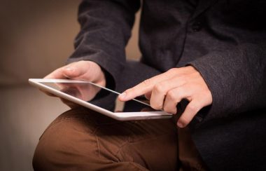 Une personne assise tient une tablette.