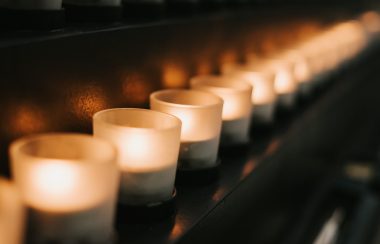 Dim candles inside holders in a row on a table.