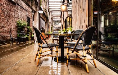 A set of tables of chairs in rows outside in an alleyway.