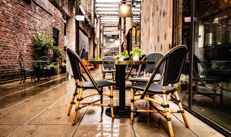 A set of tables of chairs in rows outside in an alleyway.