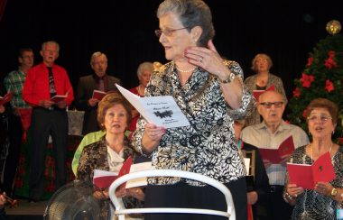 une femme avec un livre à la main et d'autres personnes derrière elle