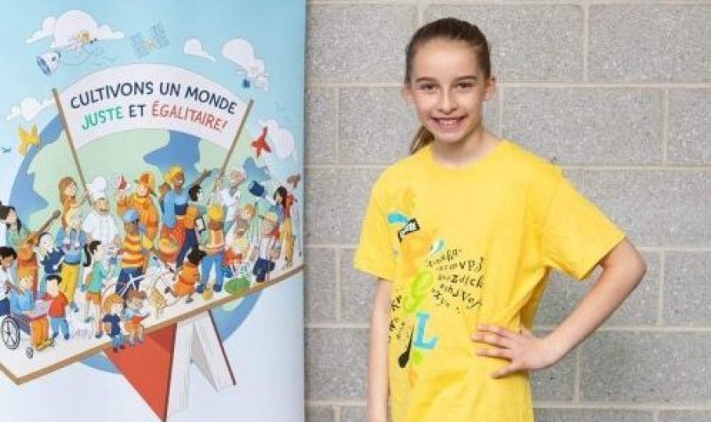 Une jeune fille portant un t-shirt jaune, pantalon noir et soulier noir à côté d'une affiche bleue à l'extérieur