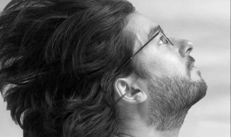 Photo promotionnelle noire et blanc de l'artiste Mclean où on le voit de profil la tête renversée par en arrière avec le cheveux qui semble flotter au vent.