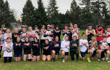 A large group of about 40 people pose for a photo on a rugby pitch in White Rock, BC.