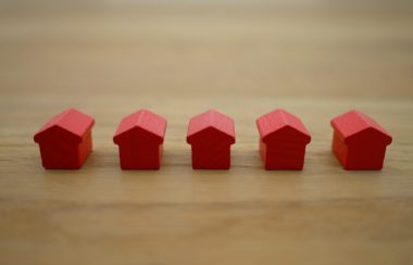 Small red toy houses sit in a row atop a table.