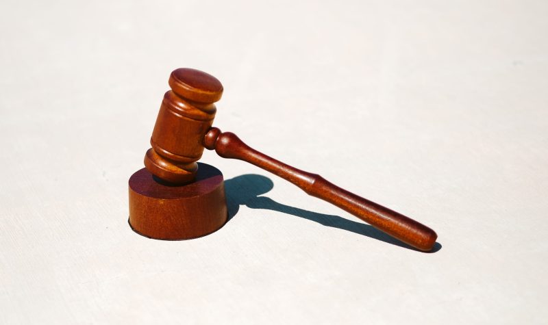 A wooden gavel rests against an off white background.