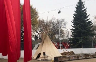 Red panels of fabric flying in light breeze and tipi on right side in a hockey rink