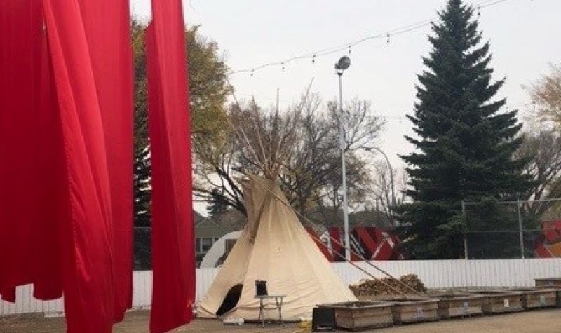 Red panels of fabric flying in light breeze and tipi on right side in a hockey rink
