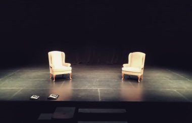On a stage, two chairs sit side-by-side on Theatre North West's stage as they ready for a performance