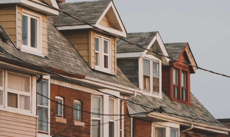 A set of beige, brown and red town houses with several windows.