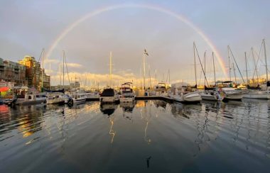 A rainbow is seen overhead at sunset near a pier in Nanaimo.