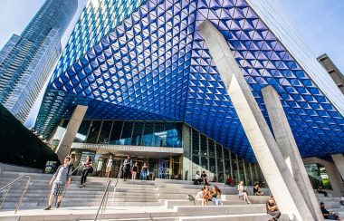 A silver and blue building with people walking up and down the stairs.