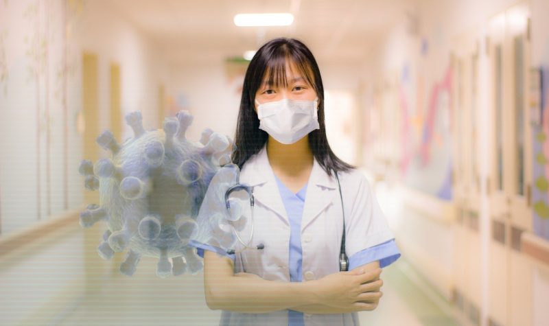 Hôpital, docteur au milieu d'un corridor d'hôpital portant un masque avec une représentation du virus à sa gauche.