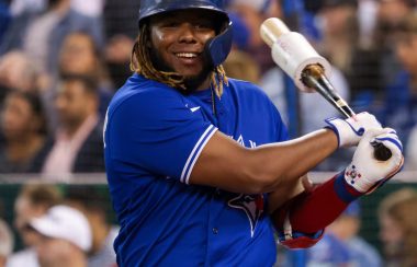 A man in a blue baseball uniform swinging a bat.