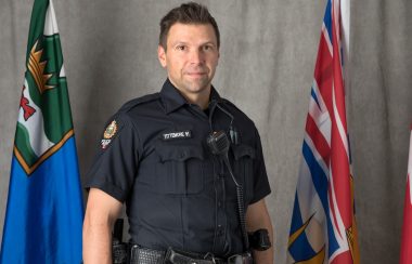A portrait of police officer wade tittemore in front of the BC and canadian flag