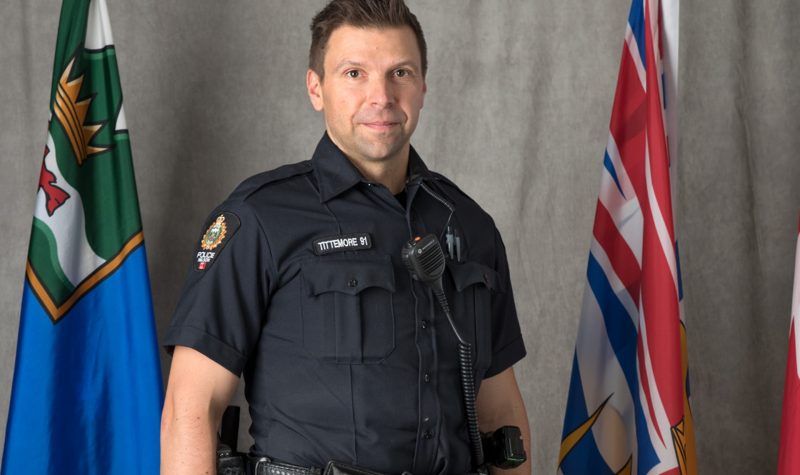 A portrait of police officer wade tittemore in front of the BC and canadian flag