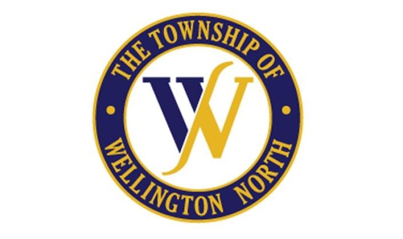 Wellington North circular logo with a half-yellow half-blue W in the centre and text around the outside rim spelling out the township name.
