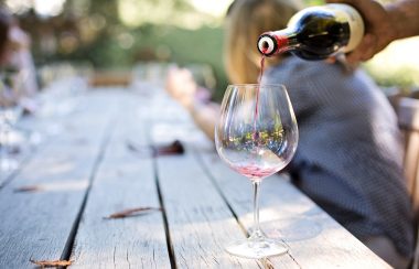 Une personne verse du vin rouge dans un verre afin de faire une dégustation.